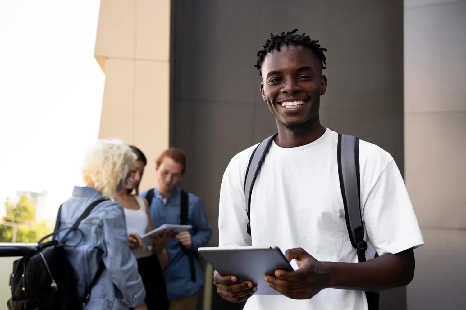 Smiling student holding a tablet outside a campus building