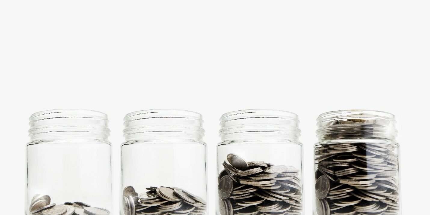 Cash Four glass tins arranged in a line with coins in them.