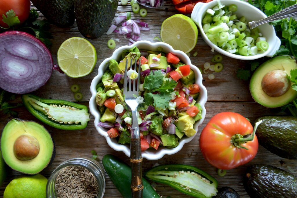An image of vegetables and fruits in a bowl and around it