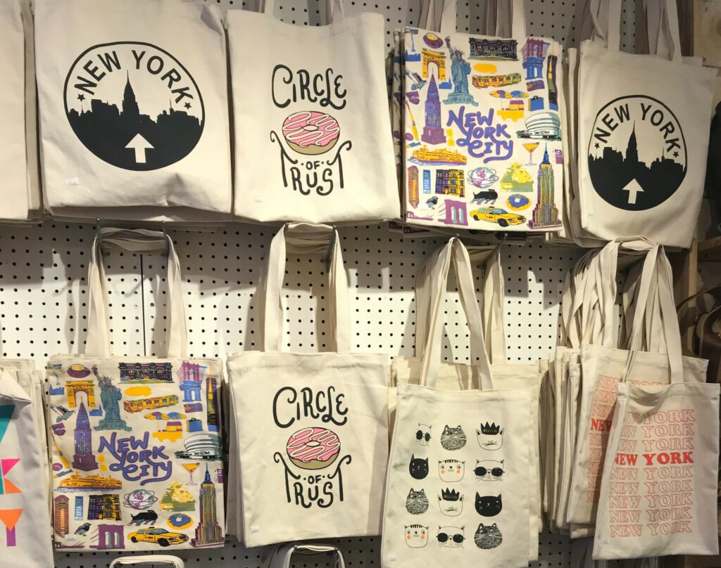 A few tote bags hanging on a dispaly wall